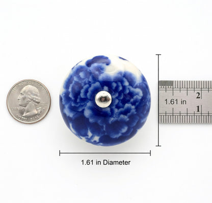 Blue floral ceramic knob with a quarter for scale on a white background