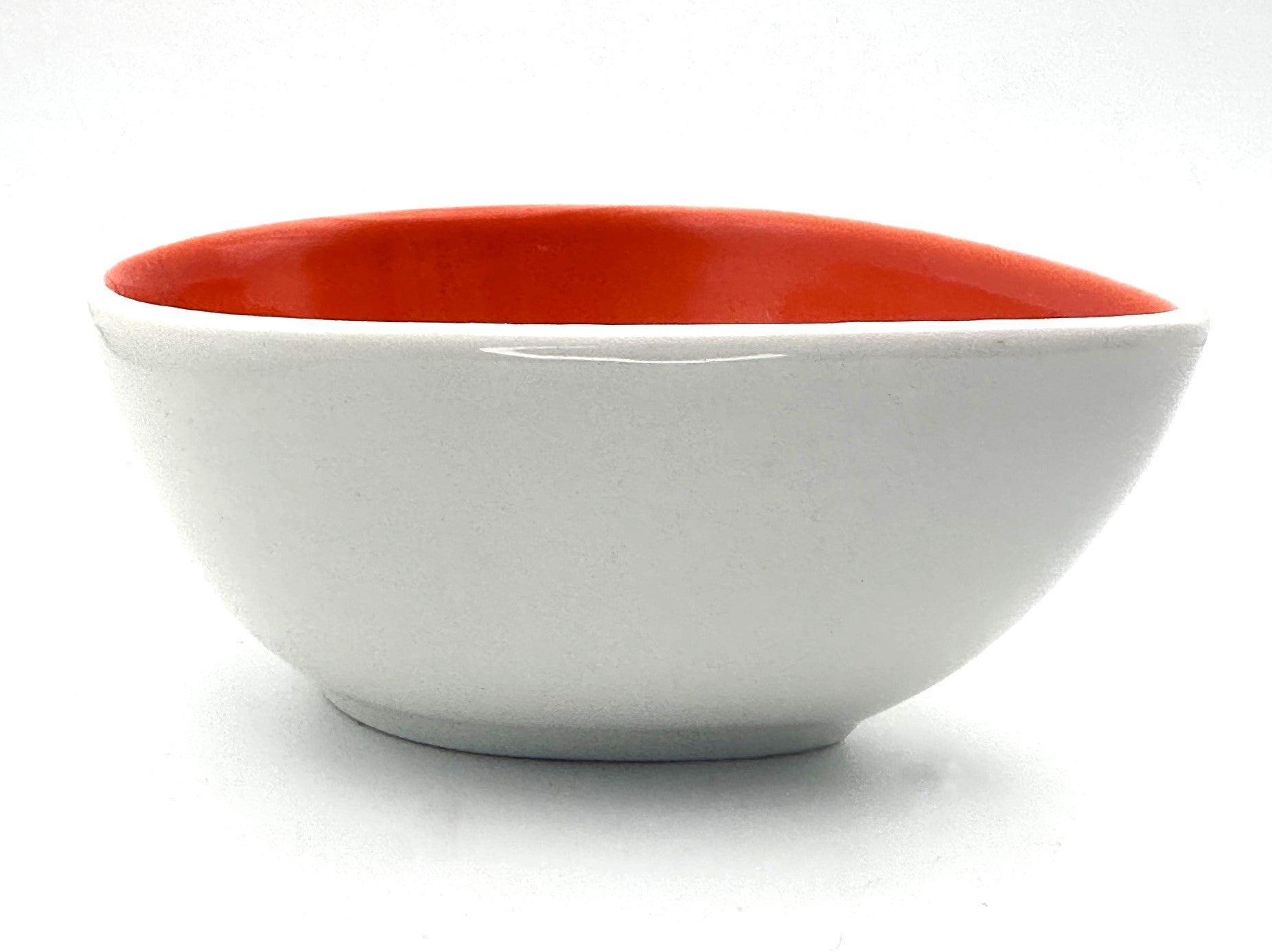 Small teardrop-shaped ceramic bowl with vibrant orange interior and handcrafted design