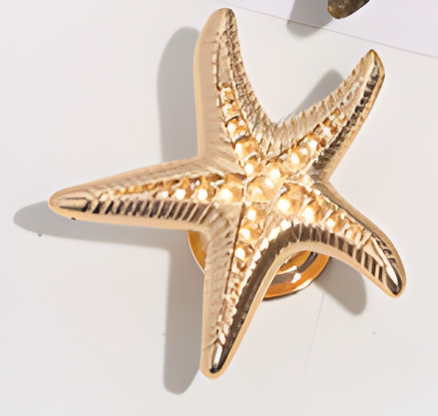 Gold starfish-shaped knob on a white background