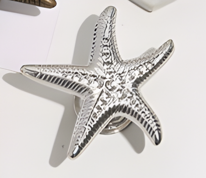 Silver starfish-shaped object on a white surface