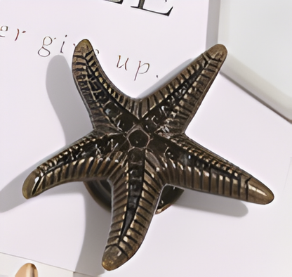 Bronze starfish-shaped object on a white surface with text in the background