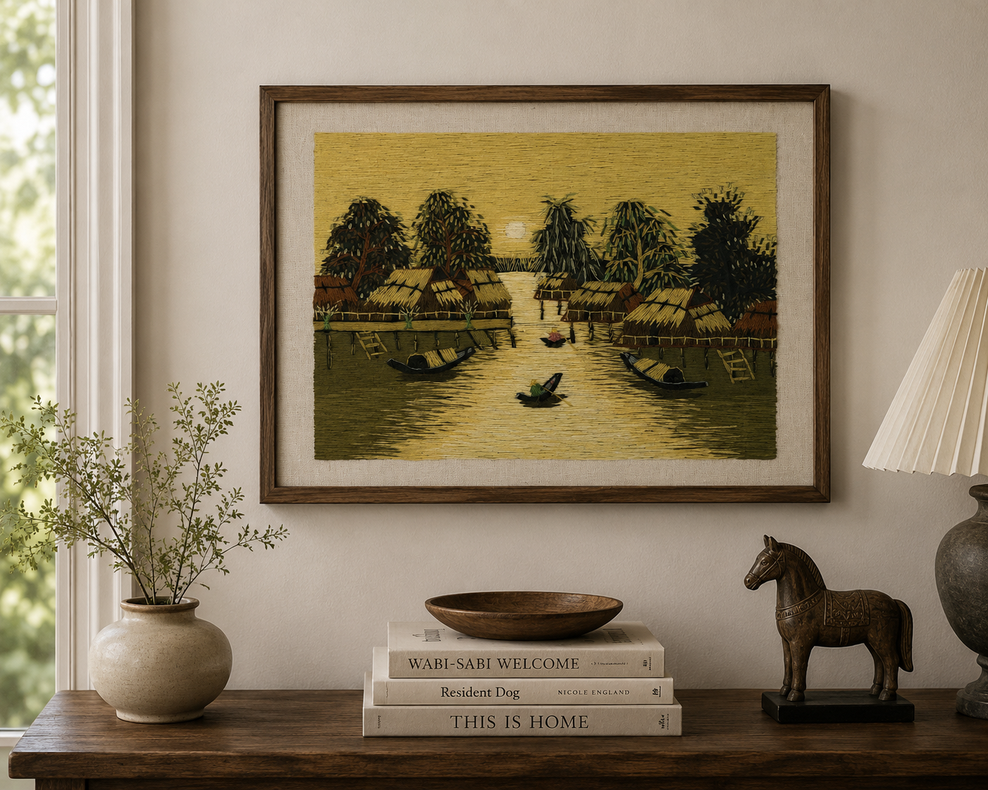 Framed Vietnamese village textile artwork displayed as statement wall décor above a mid-century sideboard.