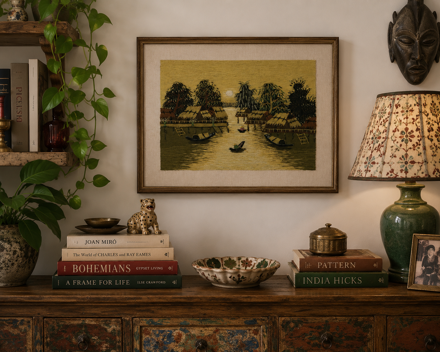 Framed Vietnamese silk thread artwork displayed above a console table in a bright neutral living room.