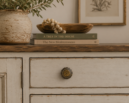 Vintage bronze medallion cabinet knob installed on a traditional dresser in a warm interior setting.