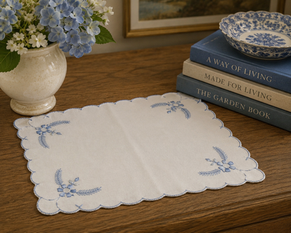 Vintage embroidered white linen centerpiece with blue floral details displayed on a farmhouse dining table.