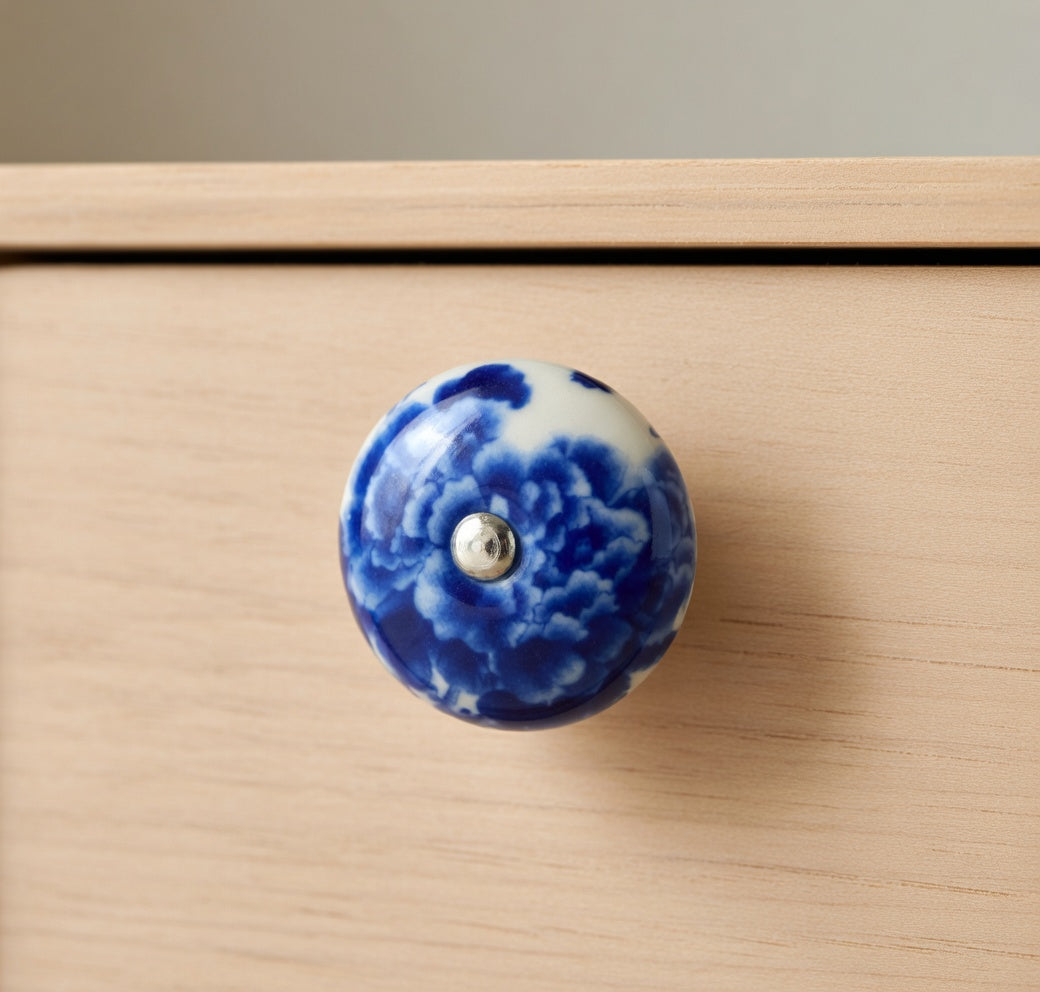Blue and white ceramic cabinet knob on a wooden drawer