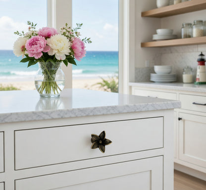 Kitchen counter with flower knob, flowers and a view of the ocean