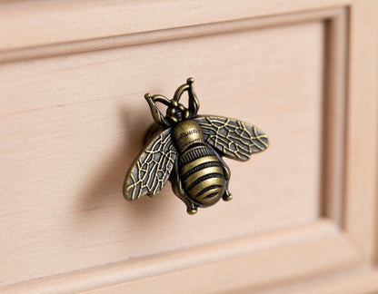 Bronze bee-shaped knob on a wooden surface
