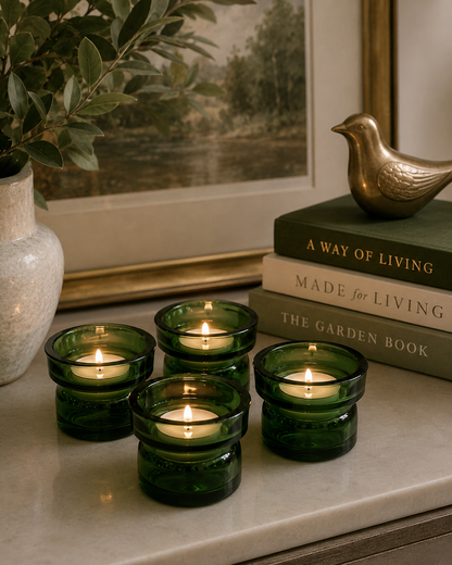 Four matching green Dansk glass candle holders arranged on a contemporary living room coffee table.