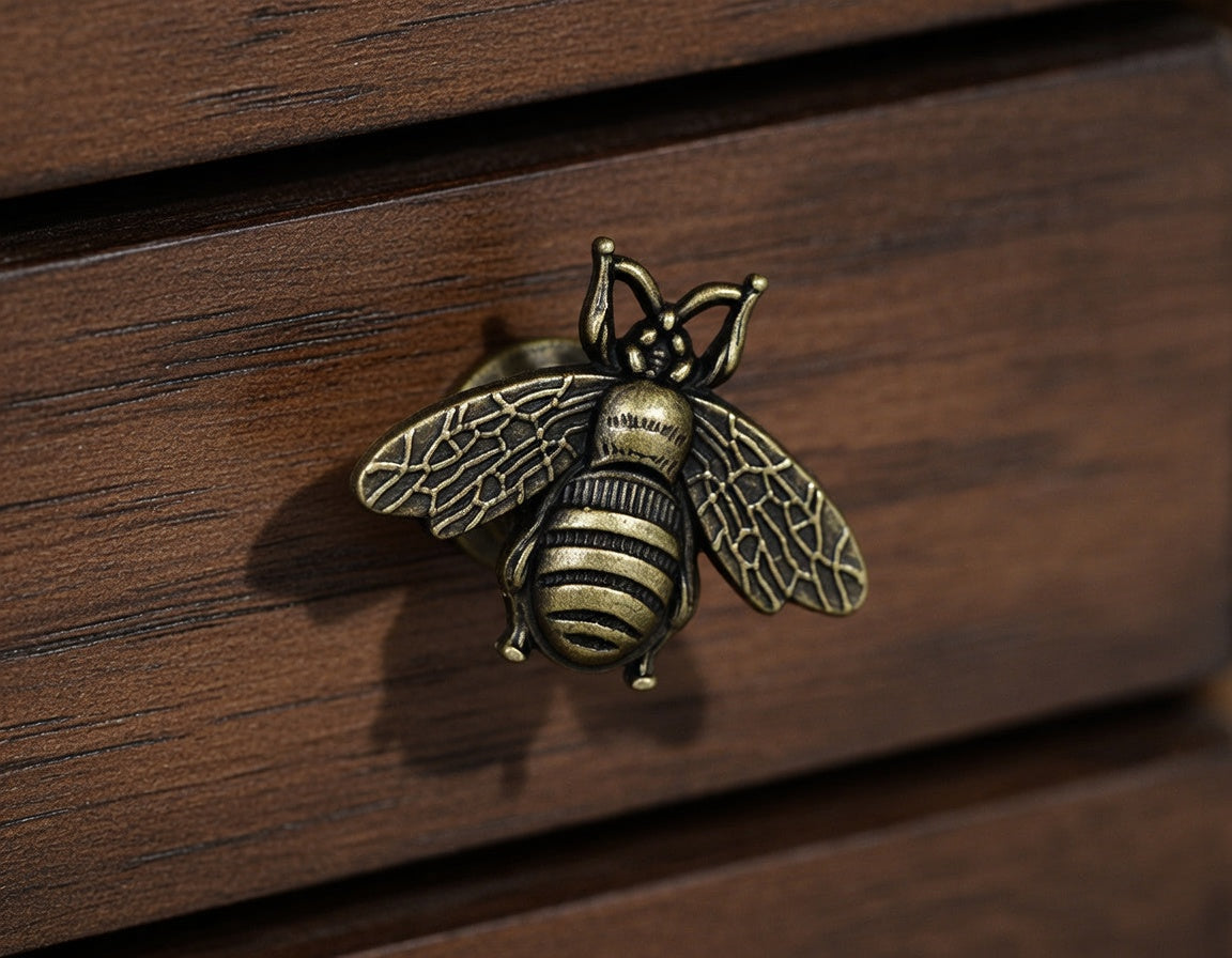 Bronze bee-shaped knob on a wooden surface