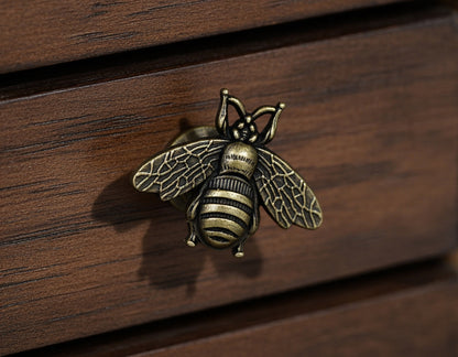 Bronze bee-shaped knob on a wooden surface