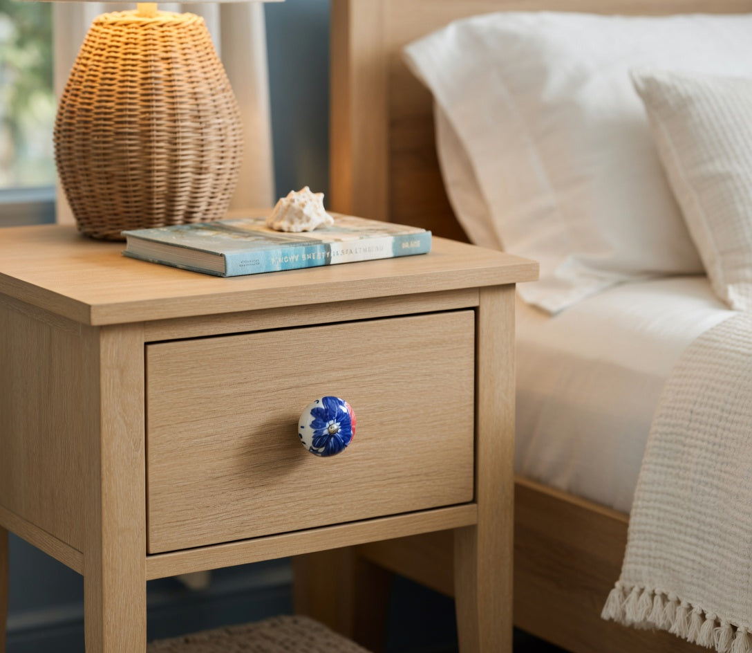 Wooden nightstand with a lamp and books next to a bed
